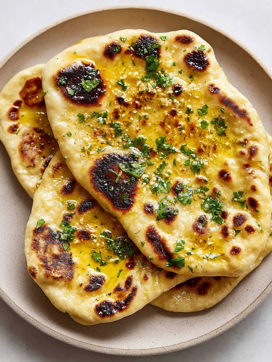 Garlic Naan Bread Recipe: The Ultimate Pillowy, Charred Flatbread Guide 3 Close-up of garlic naan bread featuring visible air bubbles, minced garlic bits, and fresh cilantro. (Garlic Naan Bread Recipe)