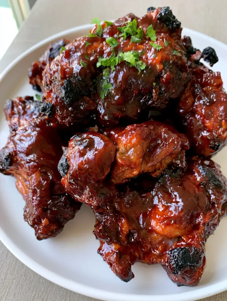 Overhead shot of a platter of Oven Baked Country Style Ribs with visible moisture and fat rendering, garnished with green parsley.
