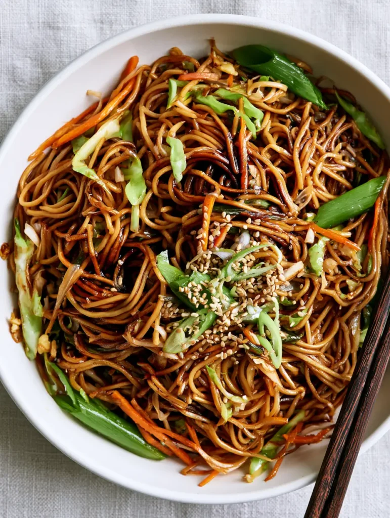 Easy Chow Mein Recipe: The Ultimate 20-Minute Glossy Stir-Fry 1 Overhead view of Easy Chow Mein Recipe in a white ceramic bowl with dark wood chopsticks.