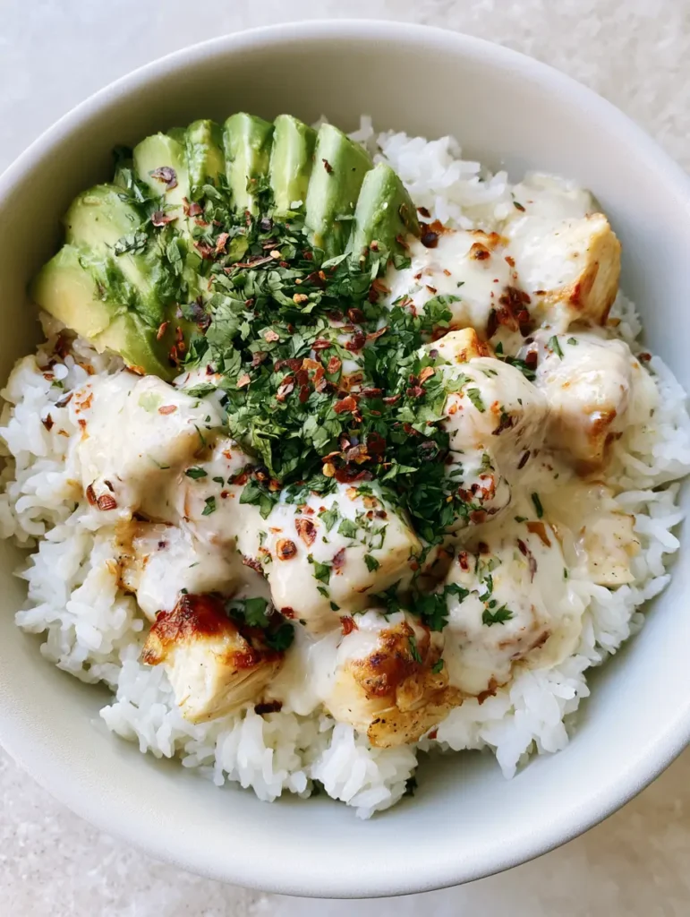 Detailed shot of seared chicken breast coated in thick coconut milk sauce garnished with chili flakes and fresh cilantro.