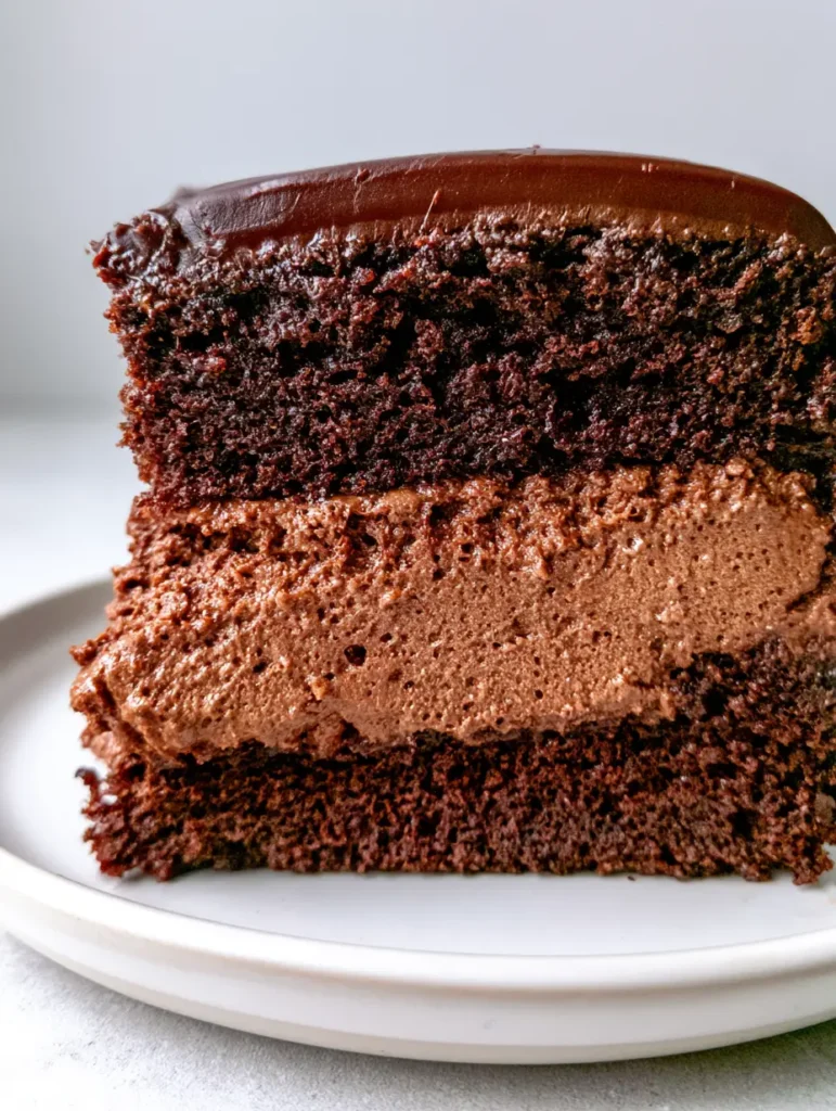 A slice of chocolate cake on a white plate showing the structural integrity of the Chocolate Mousse Cake Filling.