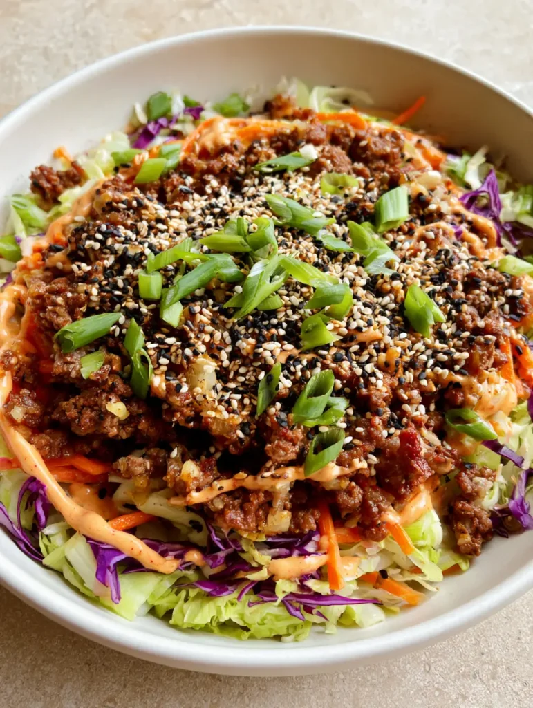 Top view of High Protein Egg Roll in a Bowl showing toasted black and white sesame seeds and bias-cut scallions.