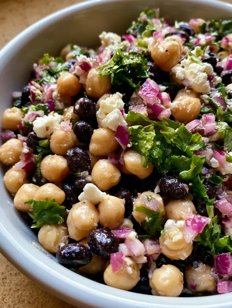 Chickpea and Black Bean Salad with Zesty Lime Dressing 1 Close up of glossy lime dressing on a Chickpea and Black Bean Salad with fresh cilantro.